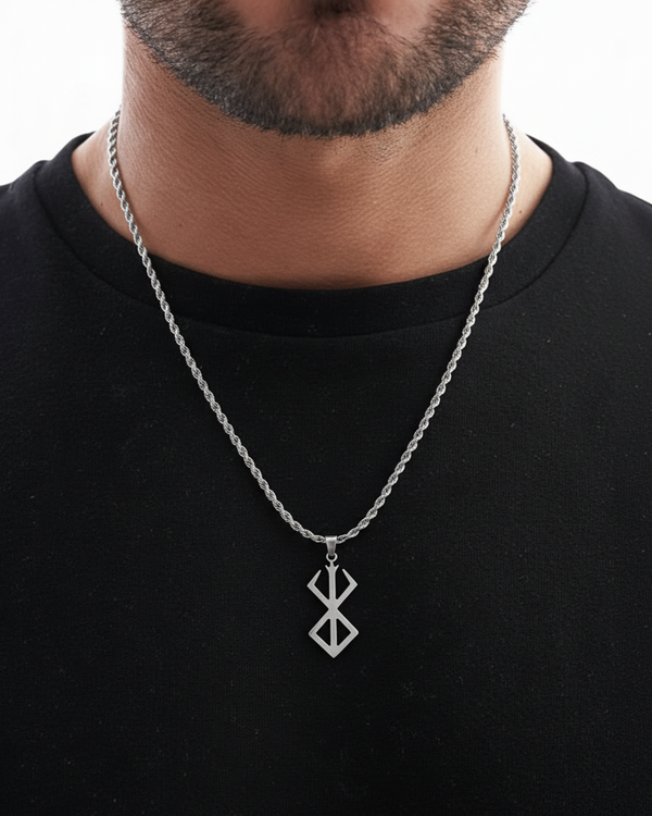 Man wearing a black shirt with a silver necklace featuring a geometric pendant.