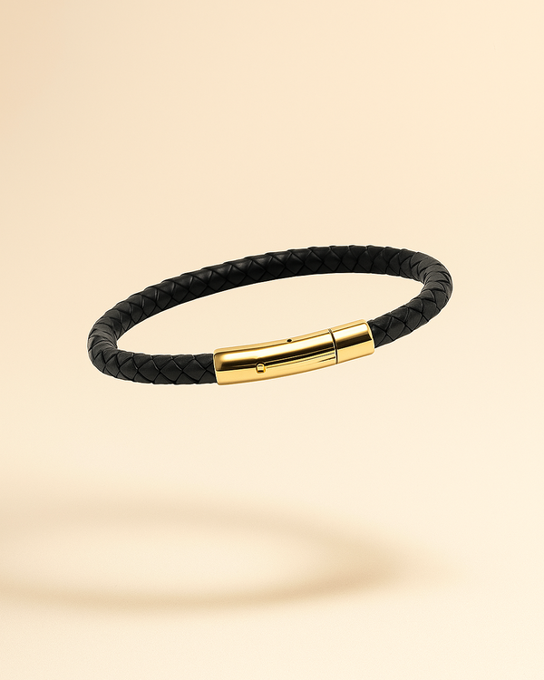 Black braided leather bracelet with a gold clasp on a beige background