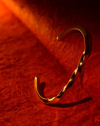Gold bracelet on a red textured fabric background