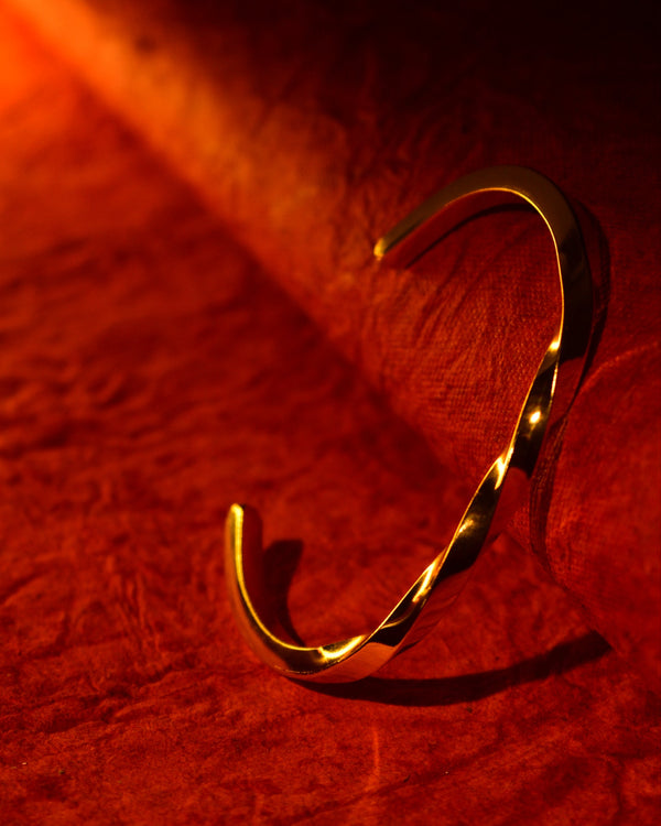Gold bracelet on a red textured fabric background