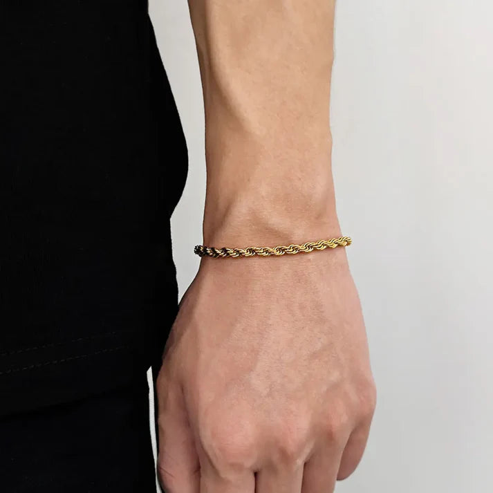Gold bracelet on a wrist against a neutral background