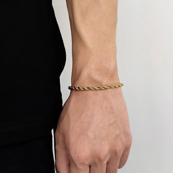 Gold bracelet on a wrist against a neutral background
