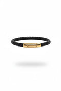 Black braided bracelet with a gold clasp on a white background